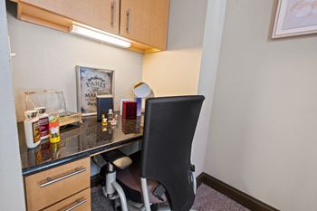 A desk with a chair in a small room with a counter top